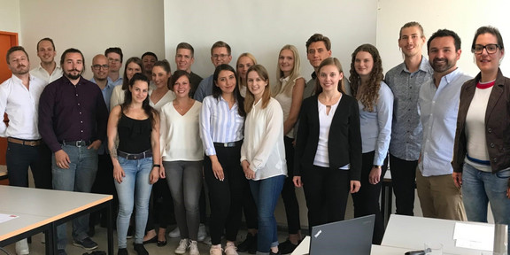 Gruppenfoto aller Teilnehmer der Präsentation vor einer Leinwand in einem Seminarraum